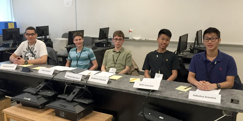 5 students seated at the competition desk.