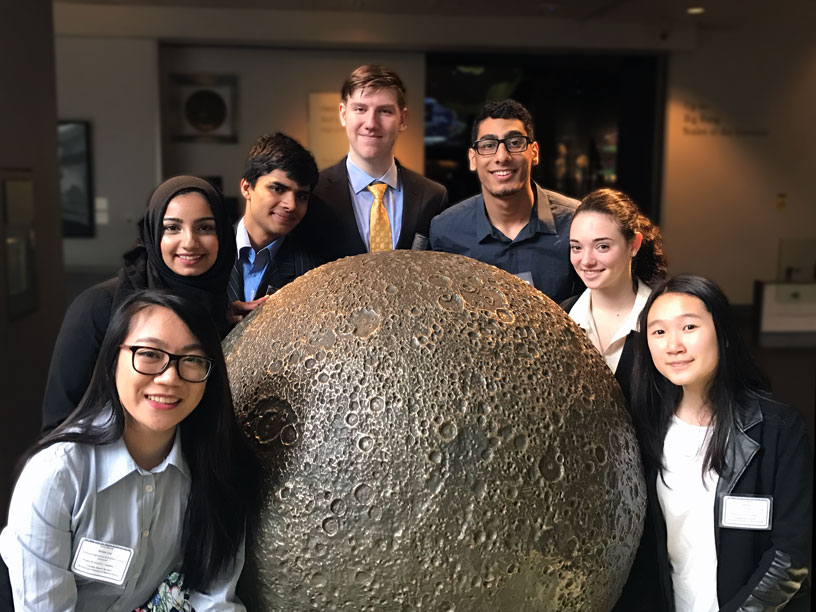 7 students arranged around a large lunar globe