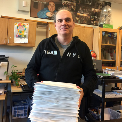Mr. Elert holding a tall stack of large white envelopes
