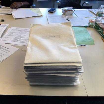 A tall stack of large white envelopes sitting on a table in the NYCSEF offices
