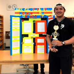 Traditional photo of the award winner holding their trophy standing in front of their poster board