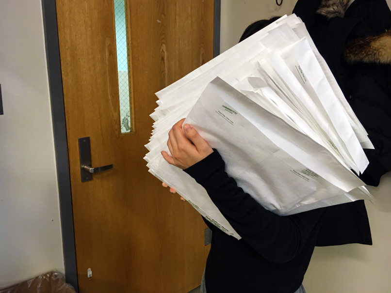 Student carrying large envelopes toward a door