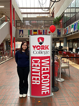 Student standing next to a York College welcome sign