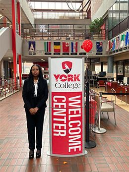 Student standing next to a York College welcome sign